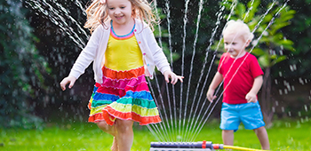 Kinder spielen im Rasensprenger