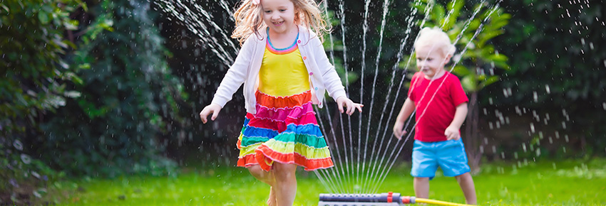 Kinder spielen im Rasensprenger