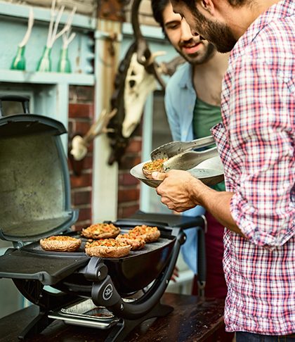 Mann grillt auf Elektro grill und gibt anderem Mann was vom Grill