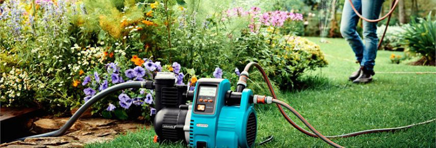 Gartenpumpe im Vordergrund im Hintergrund gie&szlig;t eine Frau