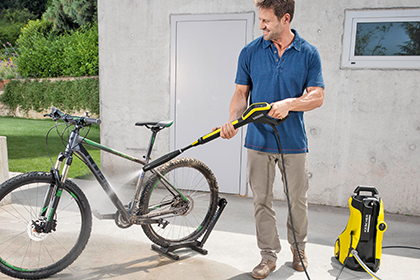 Mann reinigt sein Fahrrad mit einem Hochdruckreiniger von der Marke Kärcher.