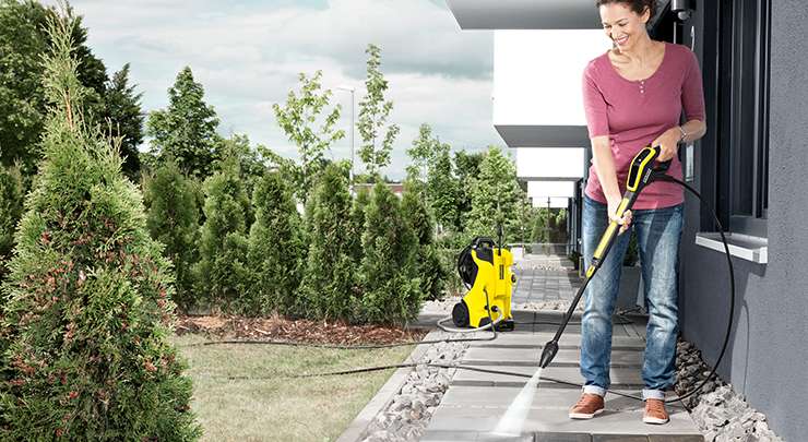 Frau reinigt ihre Terrasse aus Stein mit einem Hochdruckreiniger von der Marke K&auml;rcher.