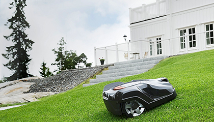 Mähroboter fährt in einem Garten bei einer Steigung.