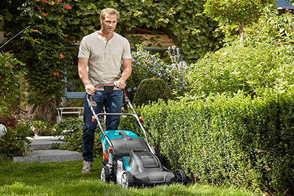 Mann mäht den Rasen mit einem Elektro-Rasenmäher.