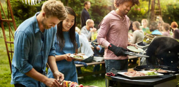 Freunde grillen zusammen im Garten mit einem Elektrogriller.