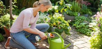 Frau bef&uuml;llt Gieskanne mit D&uuml;nger.