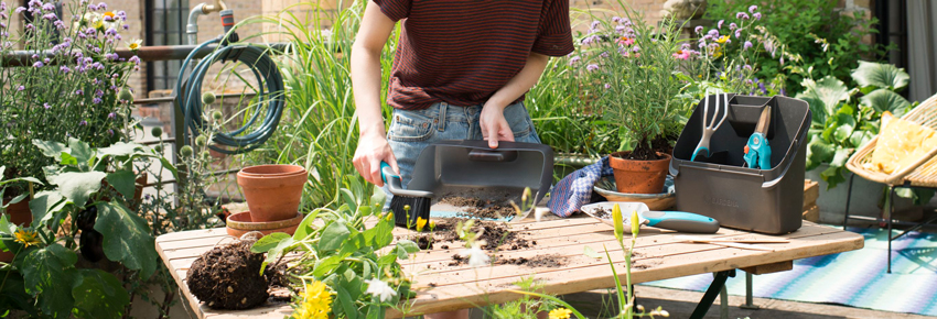 Frau arbeitet in ihrem Garten, der sich in der Stadt befindet.