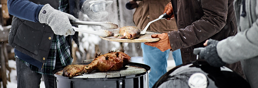 Menschen grillen im Winter mit einem Holzkohlegriller.