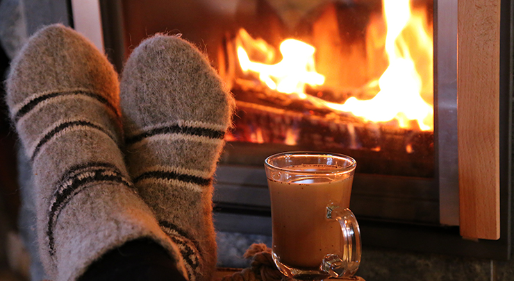 Füße mit Socken vor einem Kaminofen.