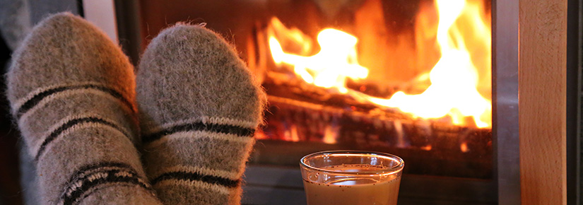 F&uuml;&szlig;e mit Socken vor einem Kaminofen.