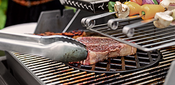 Gaskohlegrill mit Fleisch und Gem&uuml;se.