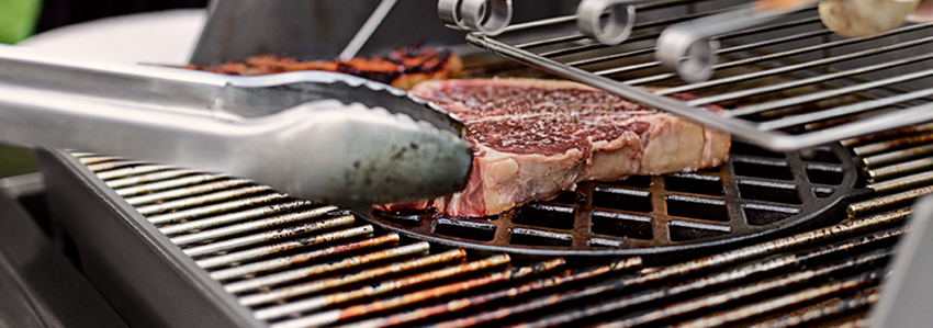 Gaskohlegrill mit Fleisch und Gem&uuml;se.