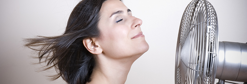 Frau steht vor einem Ventilator.