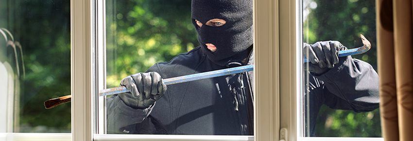 Mensch m&ouml;chte in ein Haus durch das Glas einbrechen.