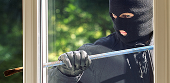 Mensch m&ouml;chte in ein Haus durch das Glas einbrechen.