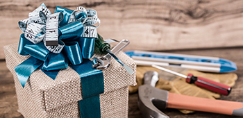 Weihnachtsgeschenk im Vordergrund, Hintergrund: Schraubenzieher und Hammer